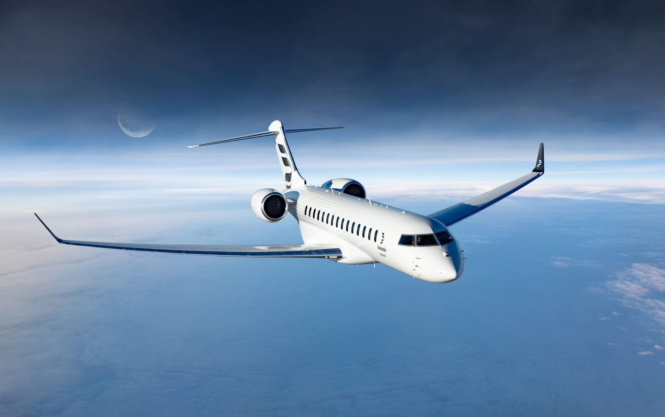 A sleek white Bombardier jet glides through the clear sky, a crescent moon casting its soft glow above the fluffy clouds.