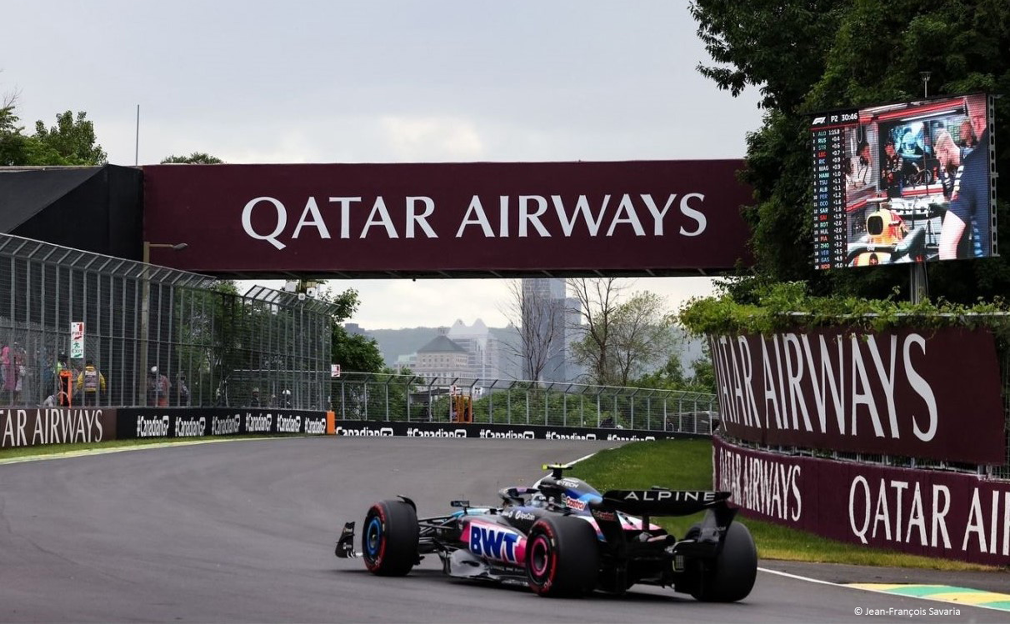 A Formula 1 car drives on a racetrack under a bridge with 