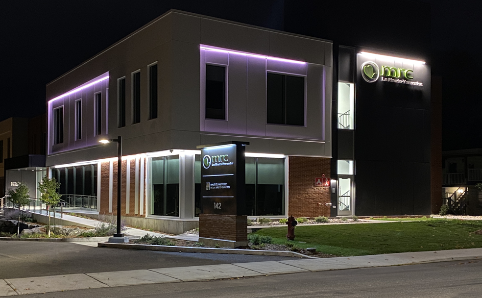 Modern two-story building illuminated at night, featuring neon lights and a sign reading 